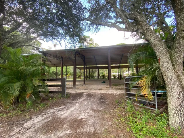 a backyard of a house with table and chairs under an umbrella