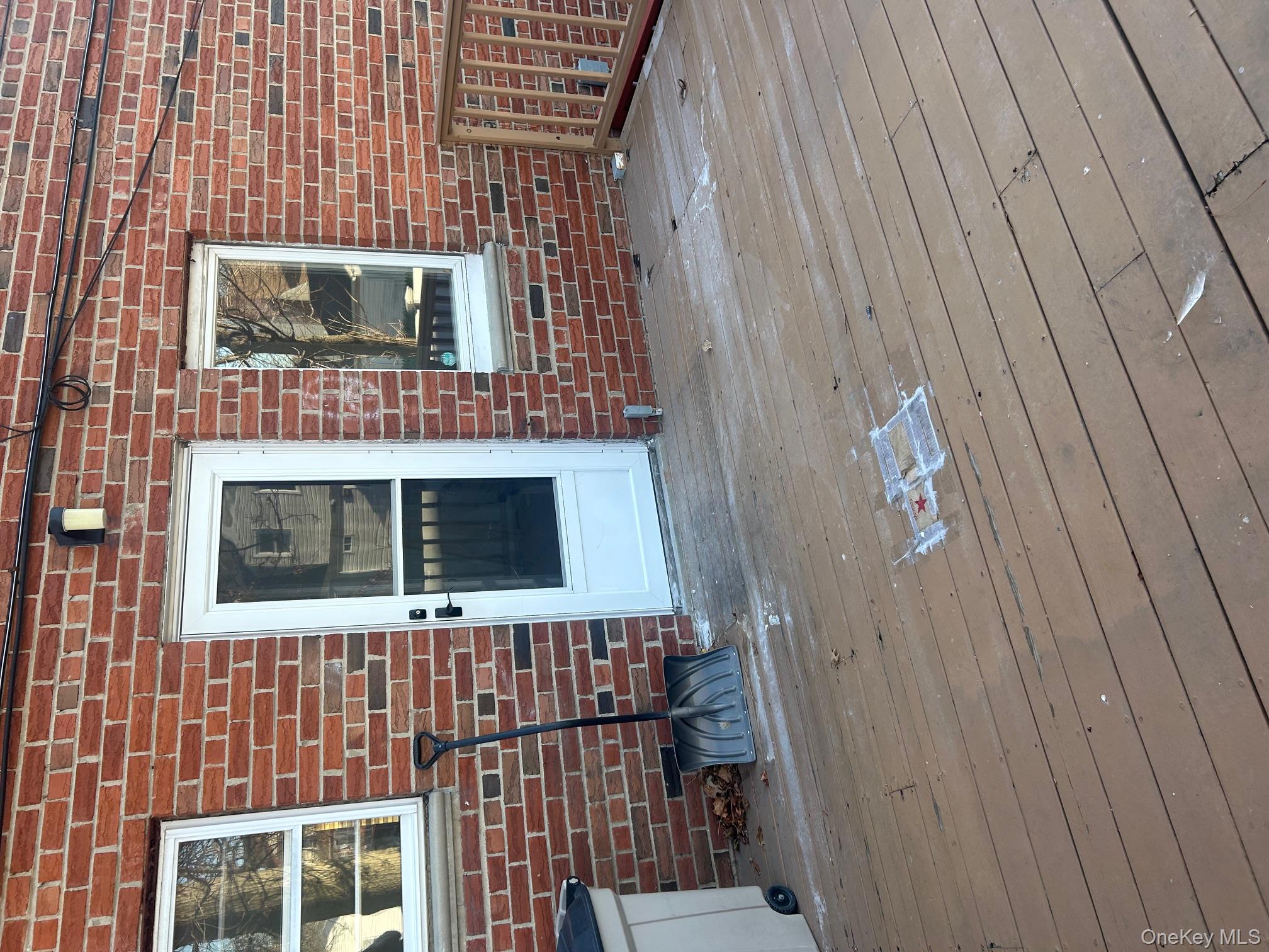 676 Front Street, Unit F Hempstead, NY 11550 - Photo 19 of 19 Entrance to property with brick siding and a wooden deck