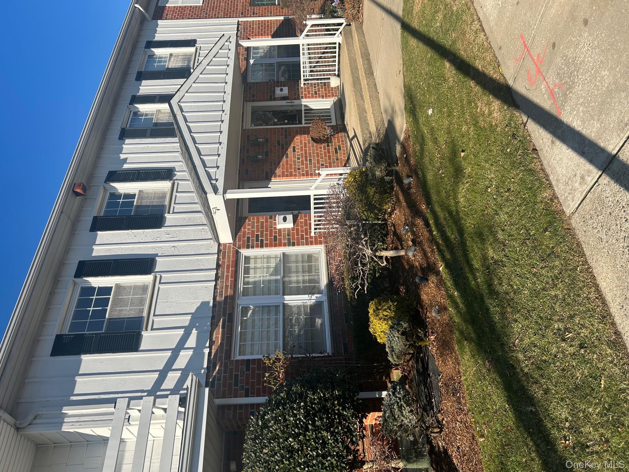 676 Front Street, Unit F Hempstead, NY 11550 - Photo 2 of 19 View of front of house featuring a porch, a front yard, and brick siding