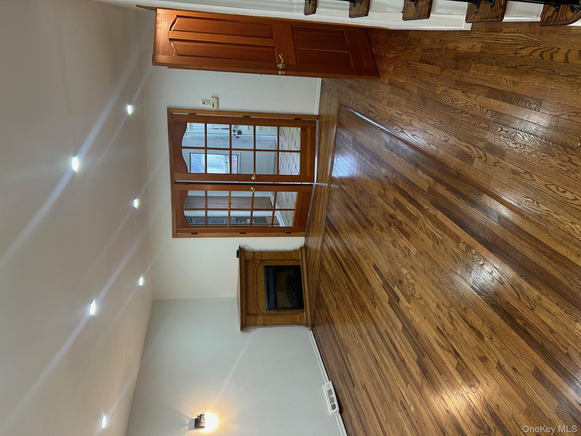 676 Front Street, Unit F Hempstead, NY 11550 - Photo 4 of 19 Unfurnished living room featuring dark wood-style flooring, a glass covered fireplace, french doors, and recessed lighting