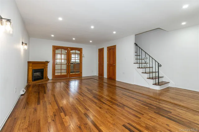 a view of an empty room with wooden floor and fireplace