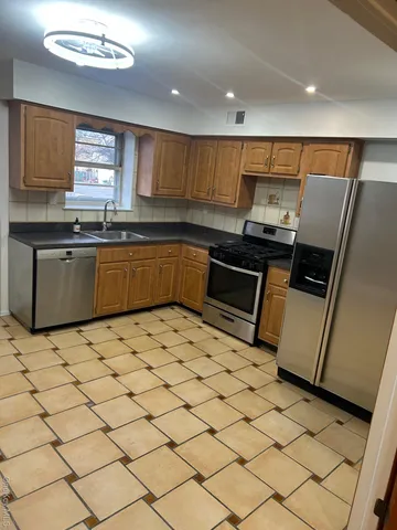 a kitchen with stainless steel appliances a sink a stove a microwave a counter top space cabinets and a window