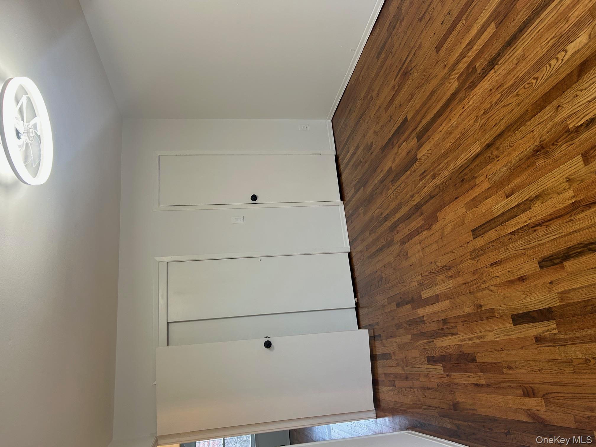 676 Front Street, Unit F Hempstead, NY 11550 - Photo 7 of 19 Unfurnished bedroom with dark wood-type flooring and a closet