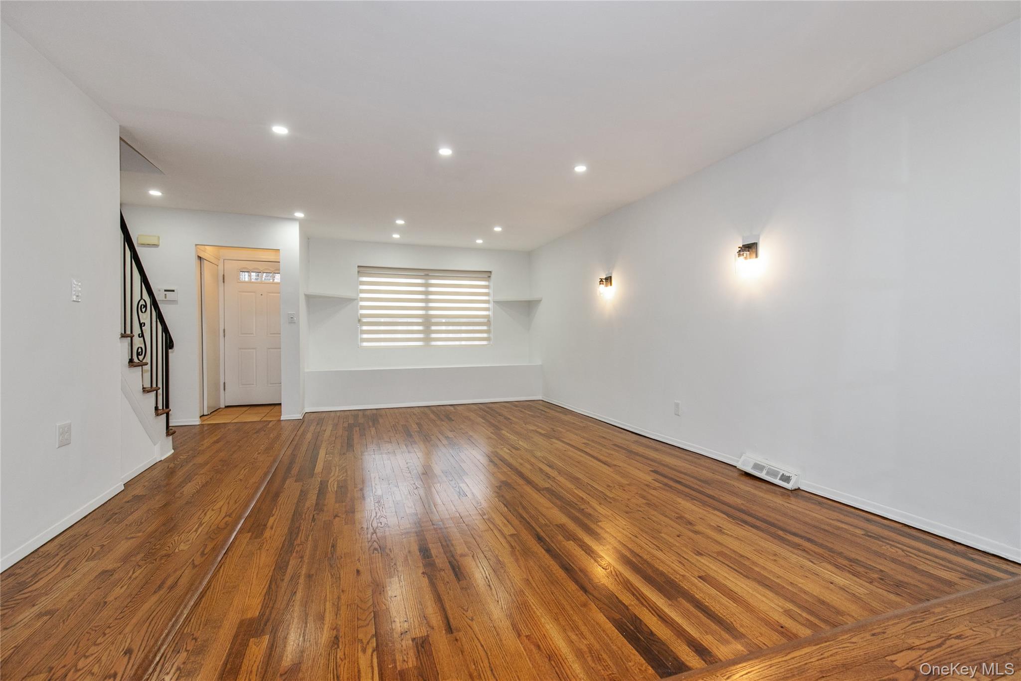 676 Front Street, Unit F Hempstead, NY 11550 - Photo 7 of 18 an empty room with wooden floor and windows