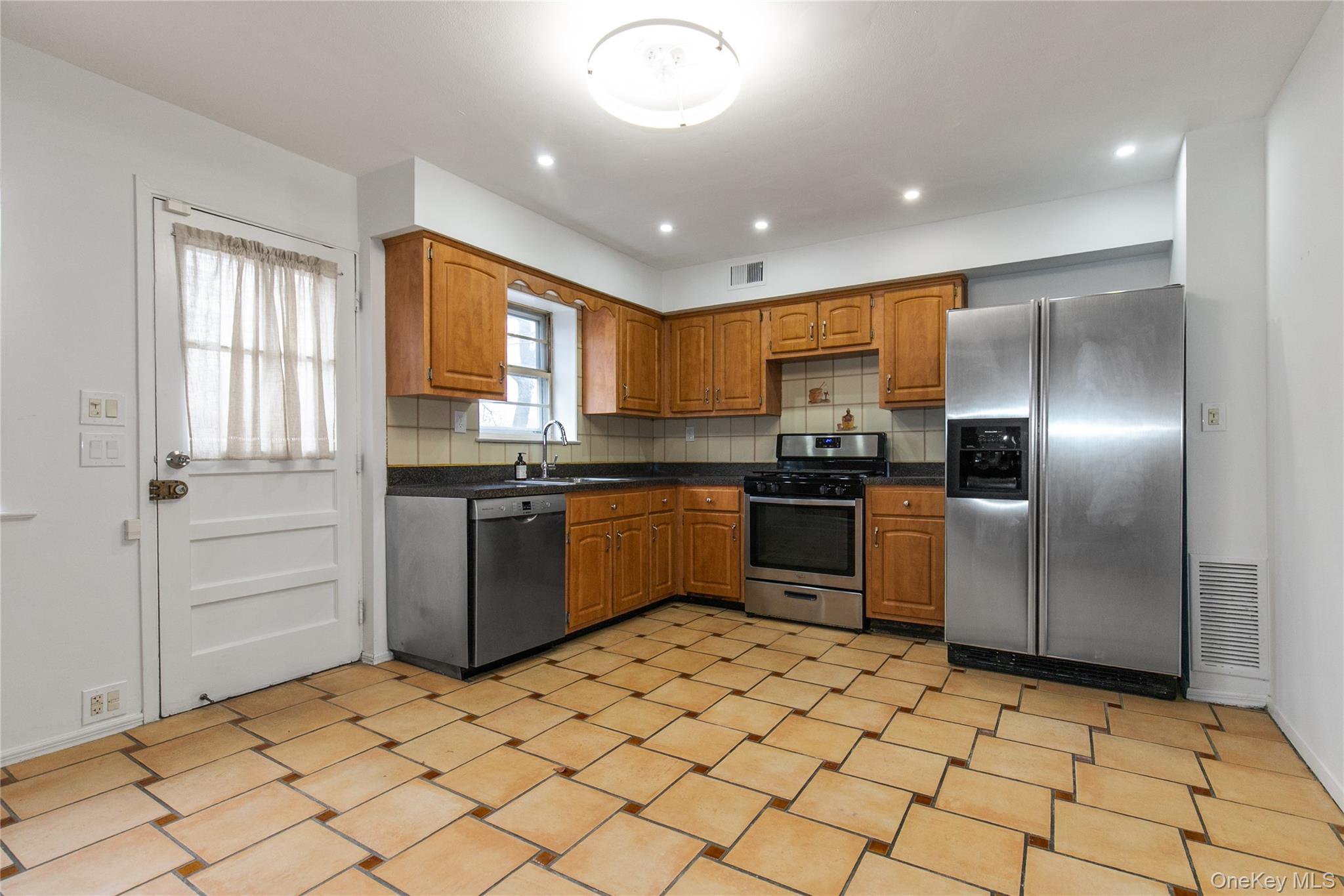 676 Front Street, Unit F Hempstead, NY 11550 - Photo 8 of 18 a kitchen with stainless steel appliances granite countertop a refrigerator and a sink
