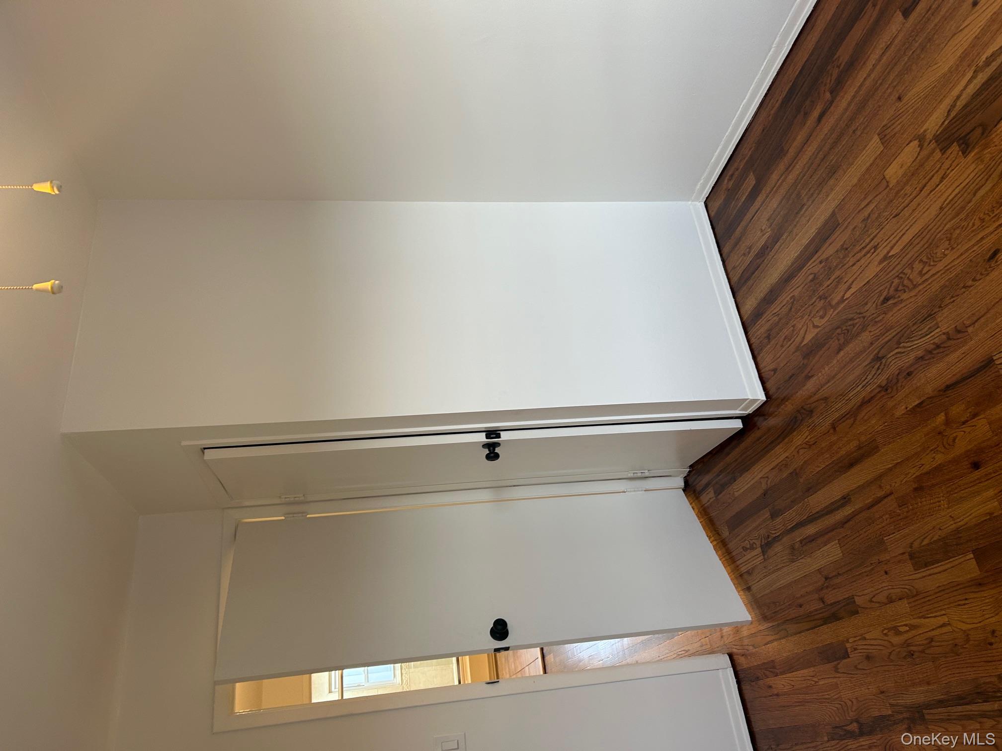 676 Front Street, Unit F Hempstead, NY 11550 - Photo 10 of 19 Unfurnished bedroom with dark wood-style floors and baseboards