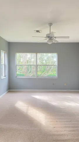 an empty room with windows and ceiling fan
