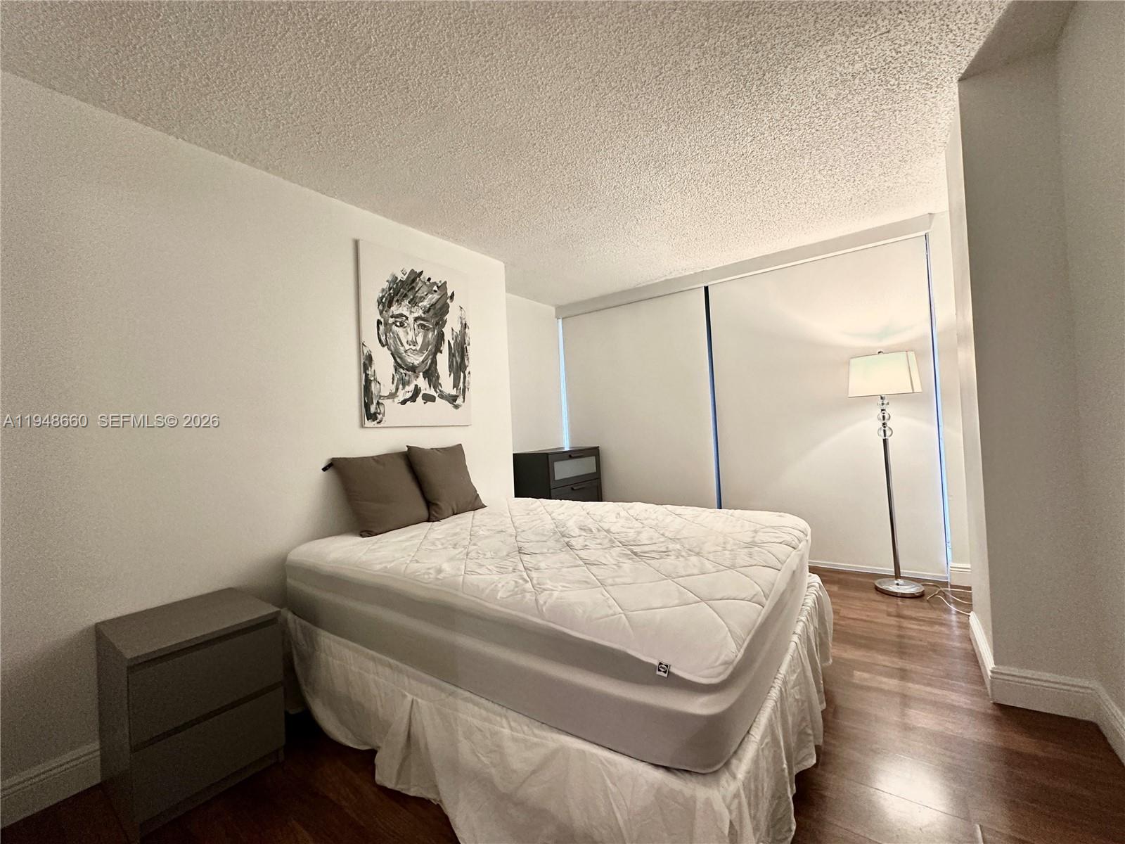 17011 North Bay Road, Unit 202 Sunny Isles Beach, FL 33160 - Photo 14 of 32 a bedroom with a bed and wooden floor