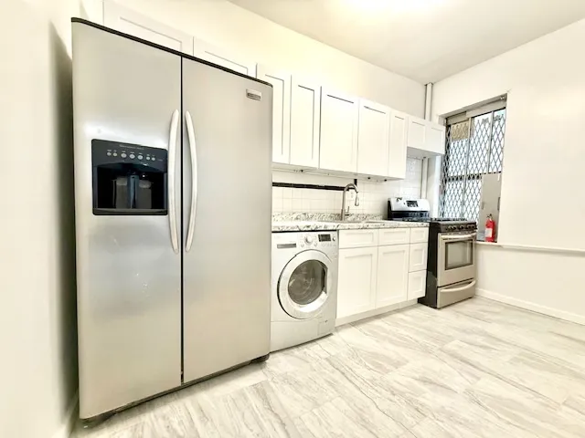 a kitchen with a refrigerator a stove and white cabinets