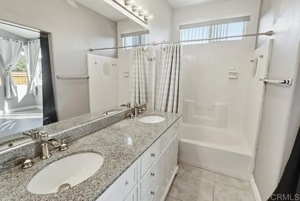 a bathroom with a granite countertop tub sink and mirror