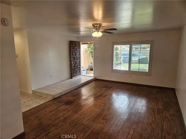 a view of an empty room with wooden floor and a window