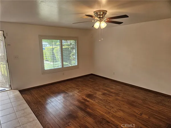 an empty room with wooden floor fan and windows