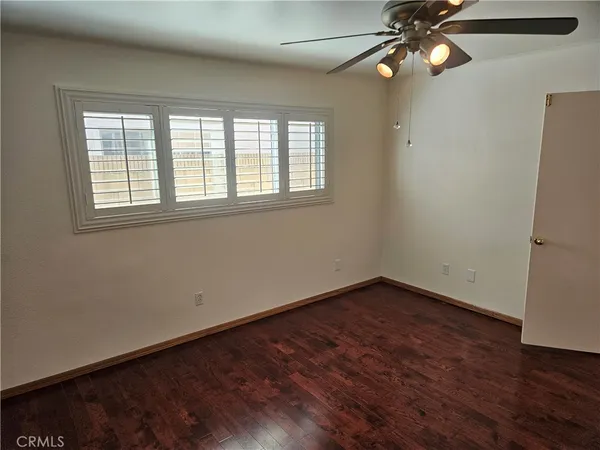 an empty room with wooden floor fan and windows