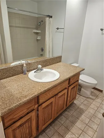 a bathroom with a granite countertop sink a toilet and a mirror