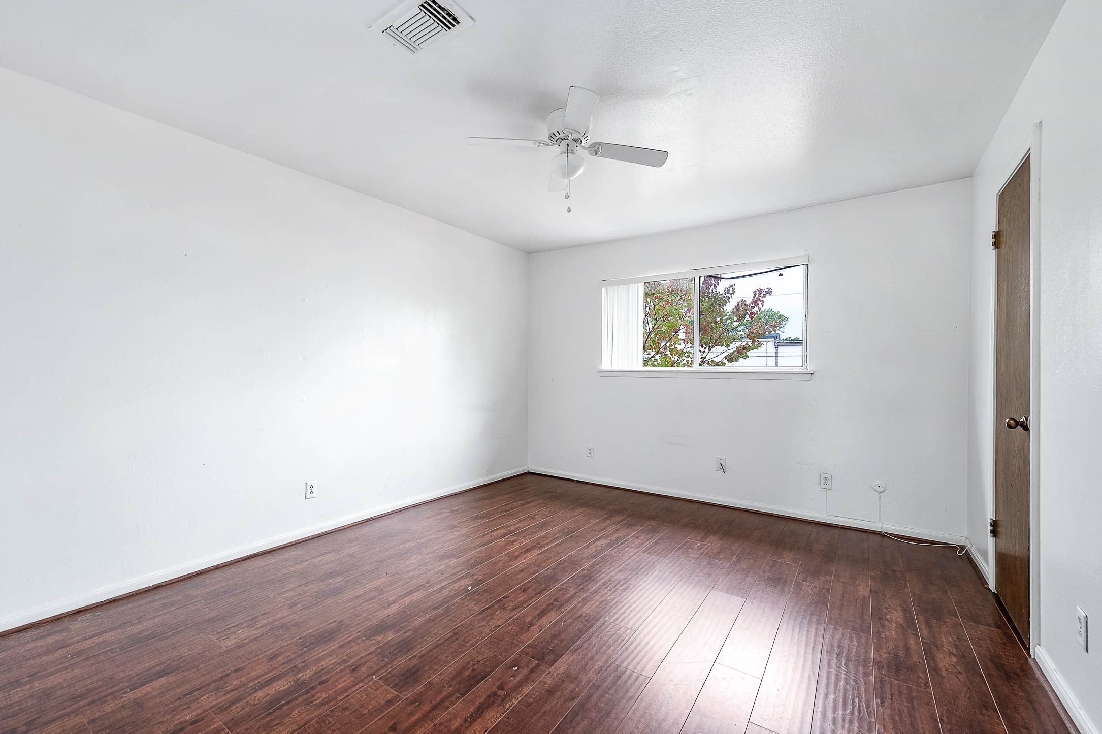 1609 Mapleton Drive Houston, TX 77043 - Photo 13 of 21 an empty room with wooden floor ceiling fan and windows