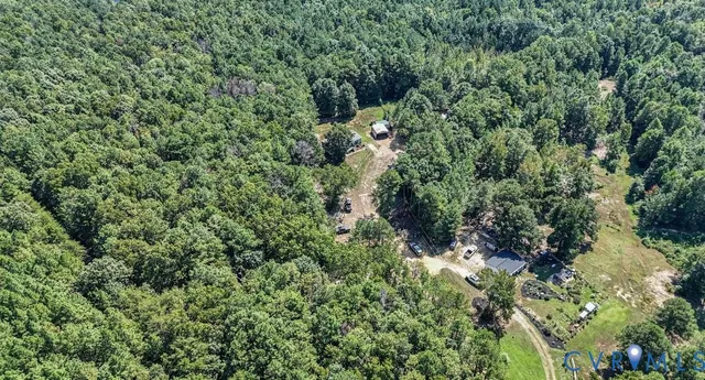 an aerial view of residential house with outdoor space and trees all around
