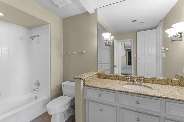 a bathroom with a granite countertop sink a toilet and bathtub