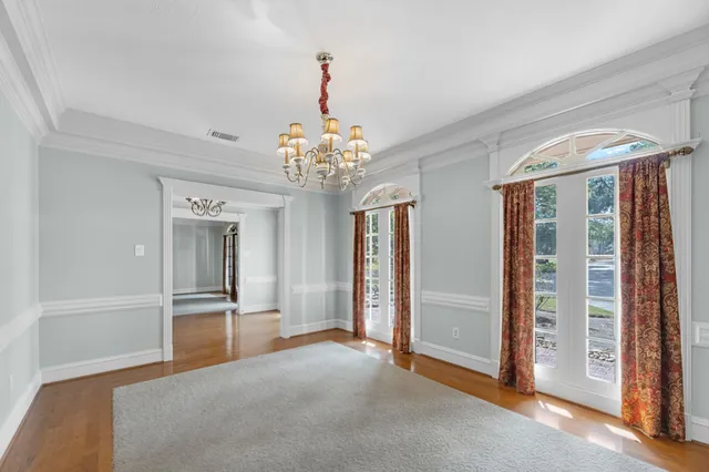 a view of a big room with chandelier front door and windows