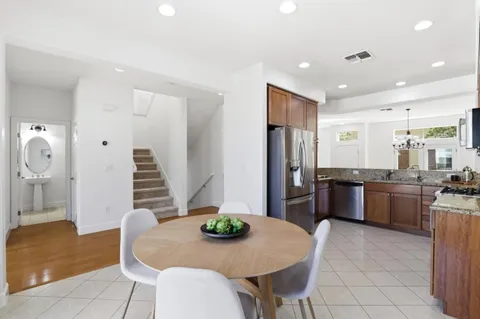 a kitchen with granite countertop a refrigerator a stove a sink a dining table and chairs