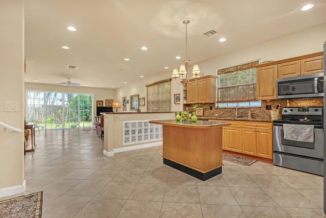 a kitchen with stainless steel appliances kitchen island granite countertop a stove a sink a microwave a refrigerator and white cabinets with wooden floor