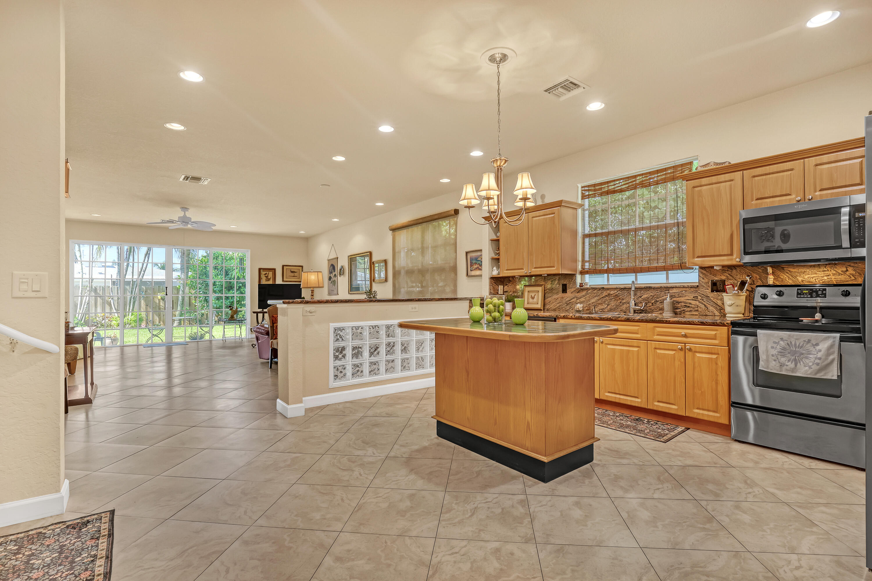 2560 Northeast 11th Street Pompano Beach, FL 33062 - Photo 3 of 18 a kitchen with stainless steel appliances kitchen island granite countertop a stove a sink a microwave a refrigerator and white cabinets with wooden floor