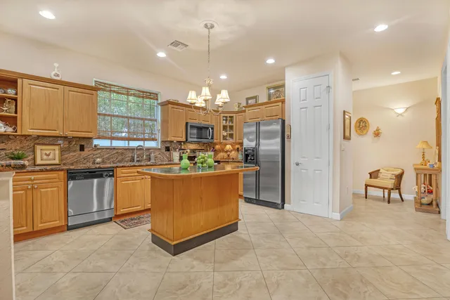 a kitchen with stainless steel appliances granite countertop a stove a sink a refrigerator and chairs