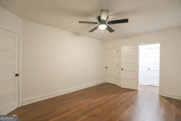 an empty room with wooden floor fan and windows