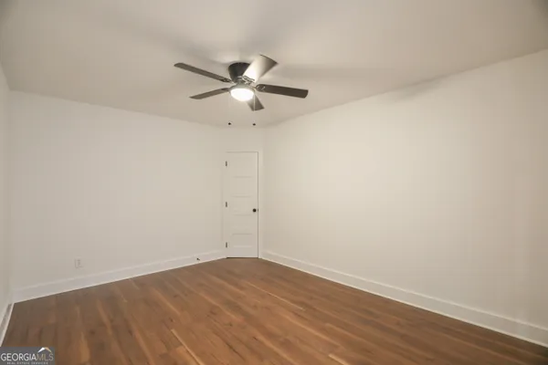 an empty room with wooden floor and a ceiling fan