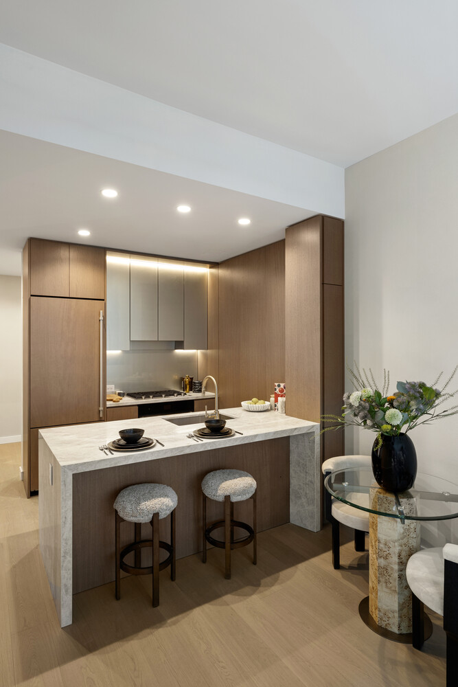 126 East 57th Street, Unit 2401 Manhattan, NY 10022 - Photo 2 of 26 a kitchen with a sink a stove and chairs