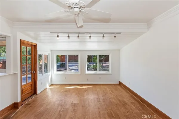 a view of an empty room with wooden floor and a window