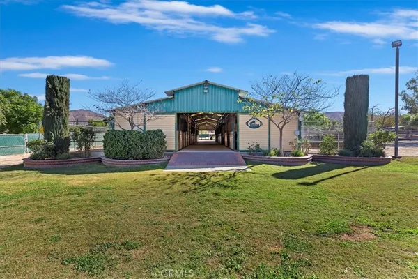 a view of house in front of a big yard with large trees