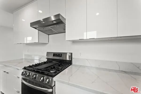 a kitchen with stainless steel appliances granite countertop a stove a sink and a white cabinets