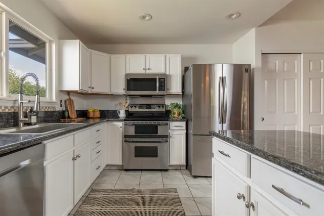 a kitchen with stainless steel appliances granite countertop a refrigerator sink and stove