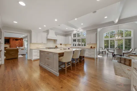 a kitchen with stainless steel appliances kitchen island granite countertop a table chairs sink and cabinets