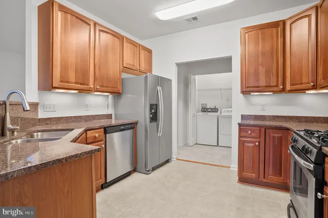 a kitchen with stainless steel appliances granite countertop a refrigerator a sink dishwasher and wooden cabinets with a granite countertops