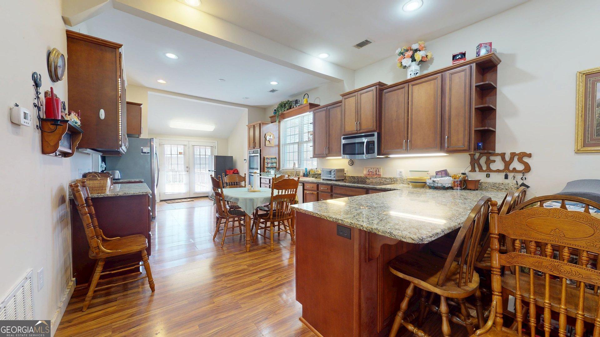 297 North Rountree Street Metter, GA 30439 - Photo 13 of 34 a kitchen with stainless steel appliances granite countertop a table chairs and a sink