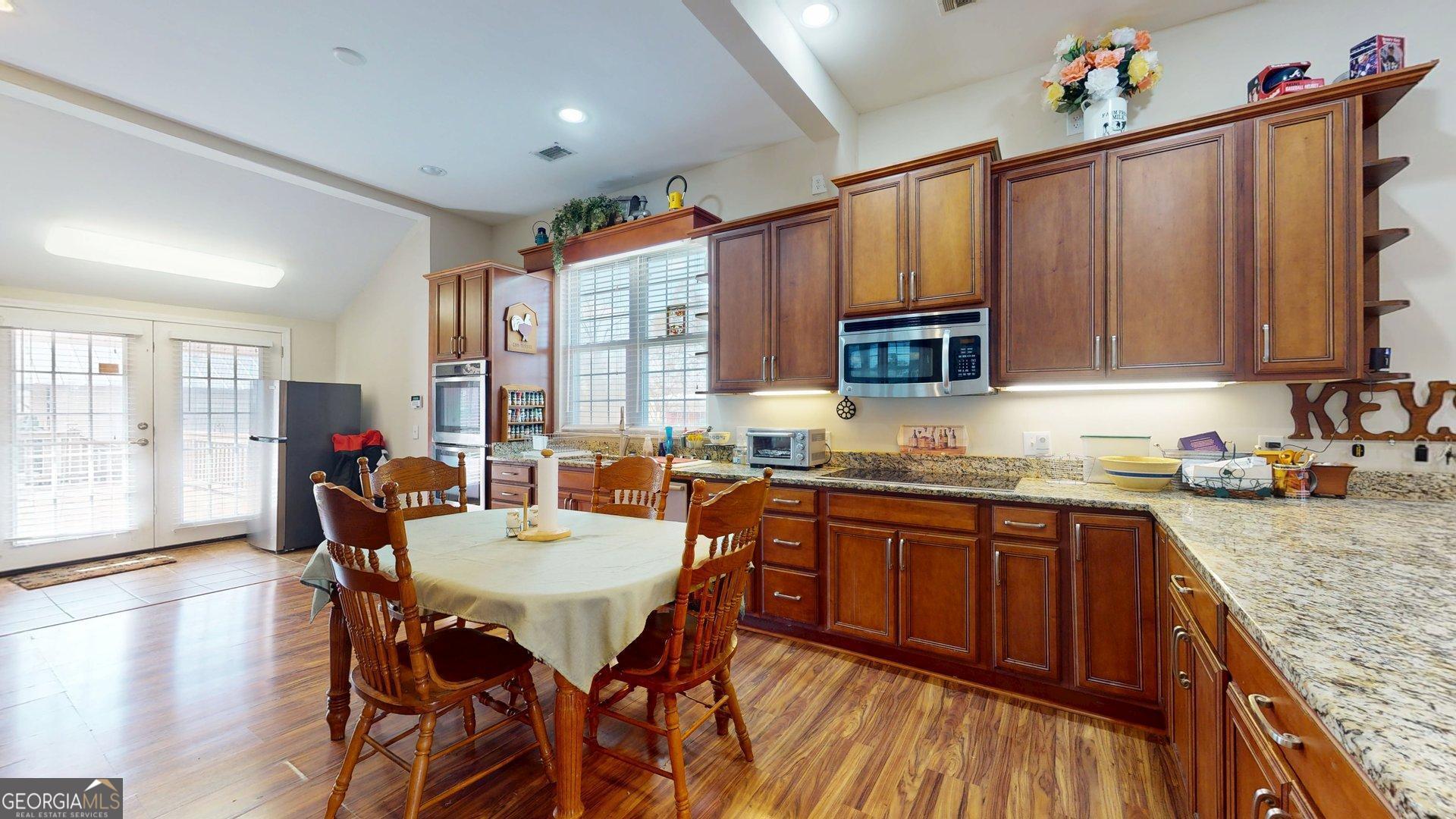 297 North Rountree Street Metter, GA 30439 - Photo 14 of 34 a kitchen with granite countertop a sink dishwasher stove and wooden cabinets