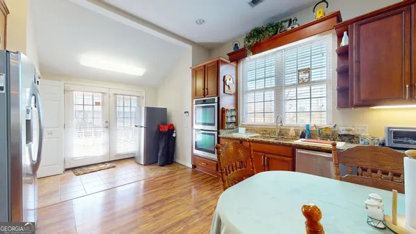 a large kitchen with stainless steel appliances granite countertop a refrigerator a sink dishwasher a dining table and chairs with wooden floor