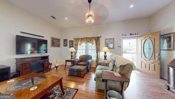 a living room with furniture a flat screen tv and kitchen view