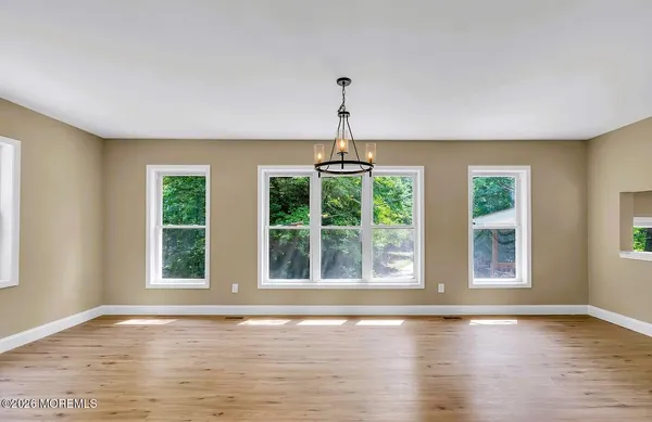 a view of an empty room with wooden floor and windows