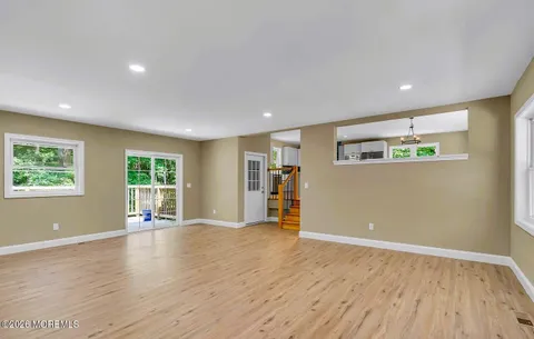 a view of an empty room with wooden floor and window