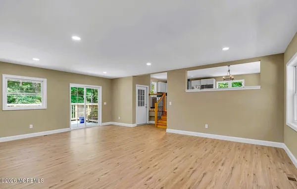 a view of an empty room with wooden floor and window