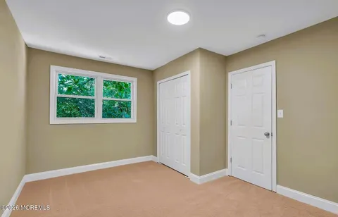 a view of an empty room with wooden floor and a ceiling fan