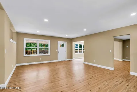 a view of an empty room with wooden floor and windows