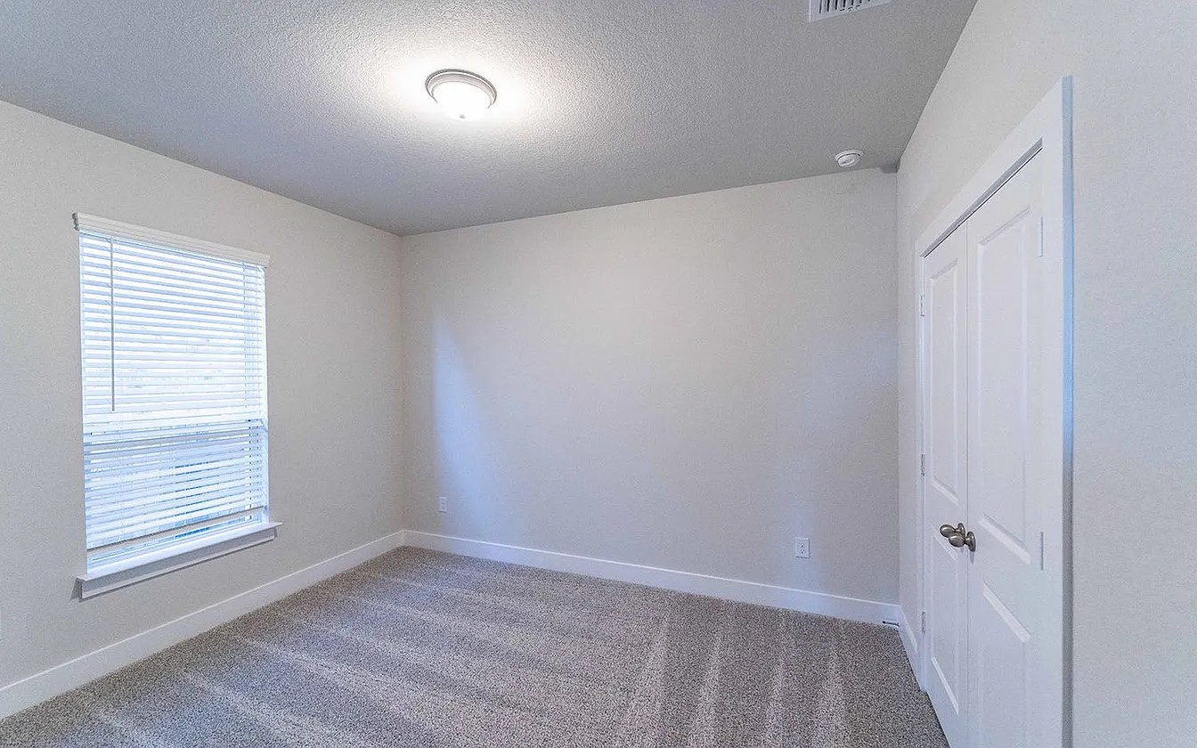 450 Durian Loop Buda, TX 78610 - Photo 15 of 17 A well-lit bedroom features plush carpeting and a convenient closet, awaiting personal touches.