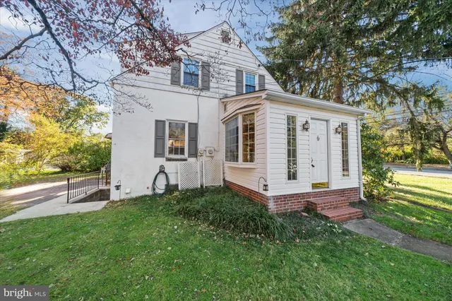 a view of a white house with a big yard and large tree