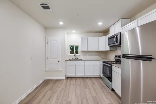 a kitchen with white cabinets stainless steel appliances and a refrigerator
