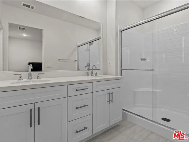a bathroom with double vanity sink and shower