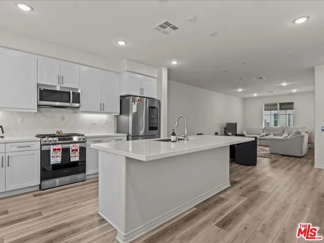 a large kitchen with kitchen island a sink a counter top space stainless steel appliances and cabinets