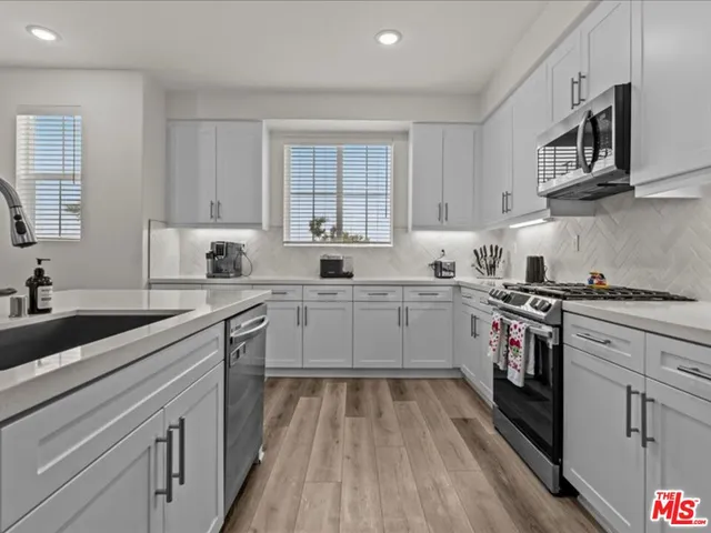 a kitchen with cabinets appliances a sink and a window